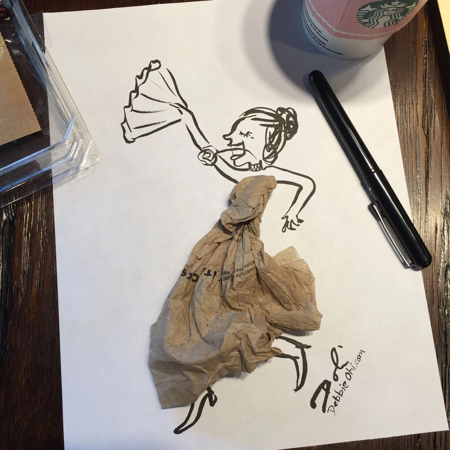 Found object art featuring a crumpled napkin that is incorporated into the drawing as a dancing woman's dress
